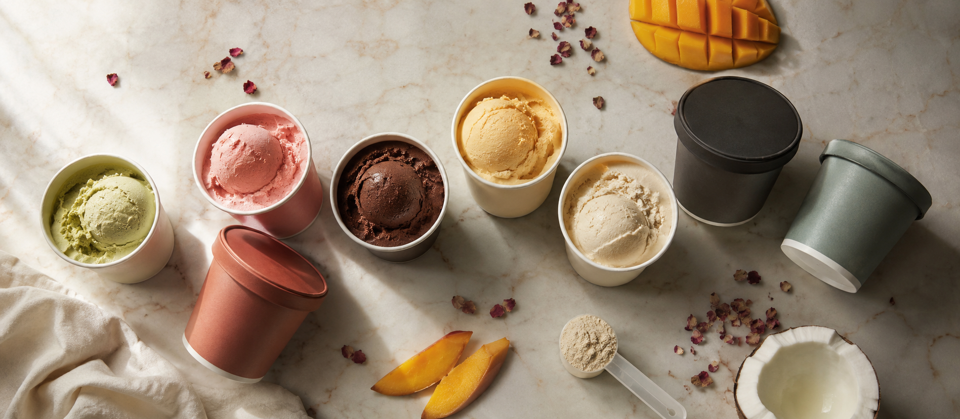 Assortment of ice cream cups and tubs from Indian brands on a warm marble surface, editorial food photography